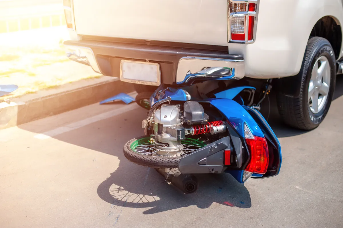 Image of a blue motorcycle after rear-ending a white truck.