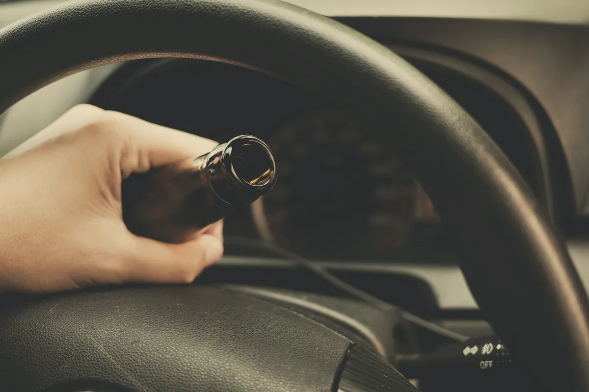 Image of a man drinking while driving to represent the punishments of doing so