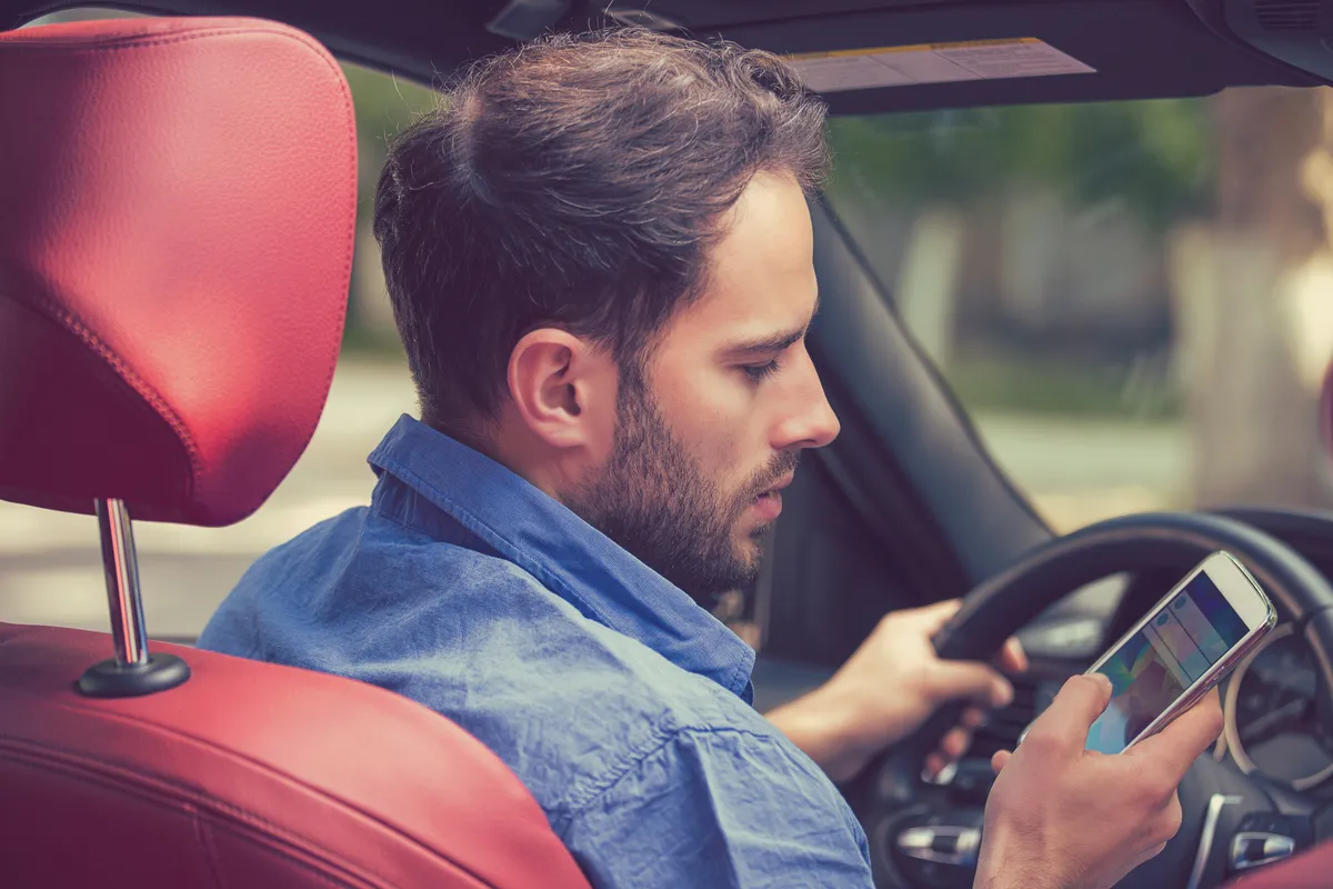 Image of a man texting while driving to represent negligent driving.