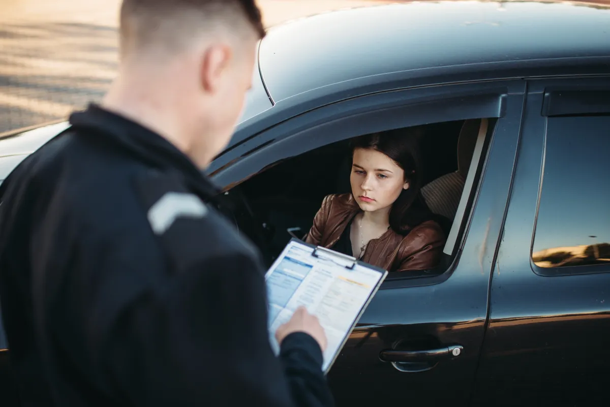 Image of a police officer writing a traffic ticket to a driver to represent cell phone tickets in Nevada