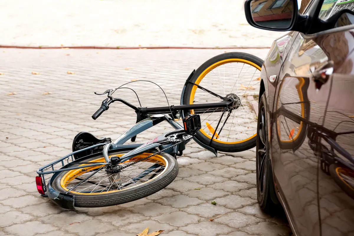 a bicycle that is laying on the ground next to a car