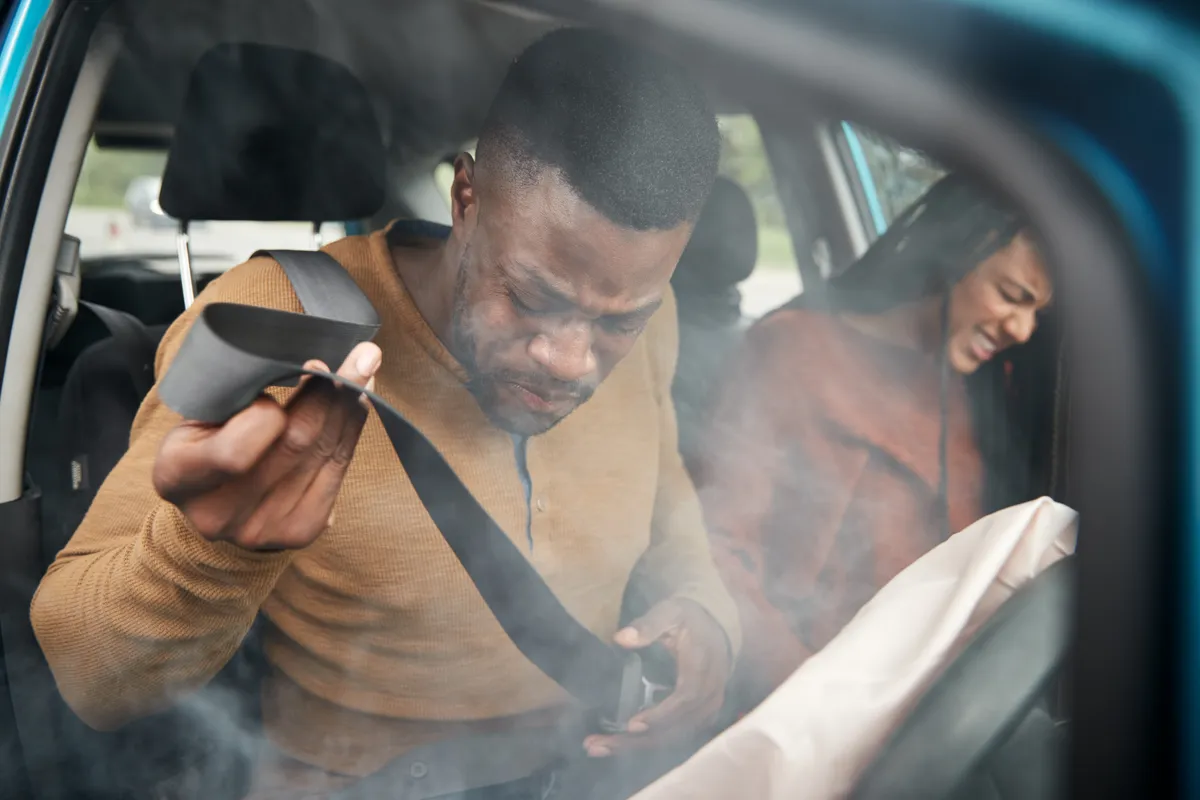  a man and woman sitting in a car looking at a cell phone