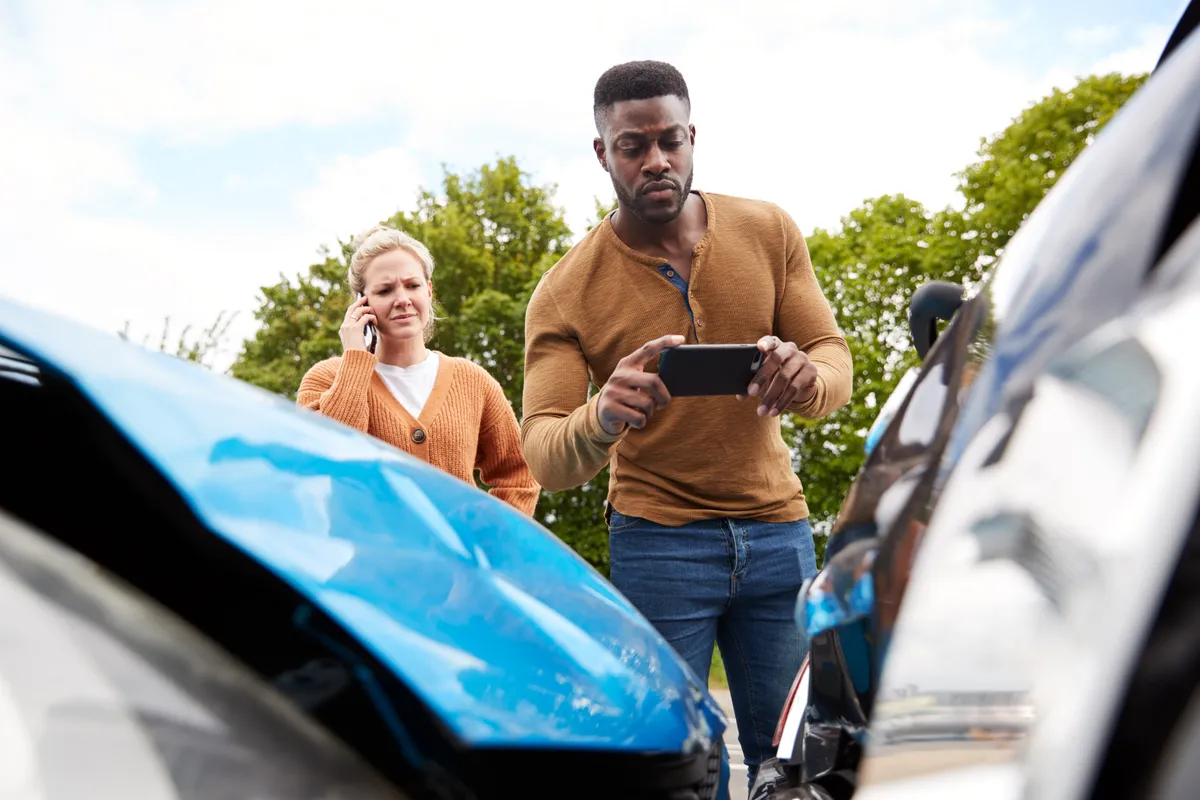  a man and woman standing next to a car with a broken hood