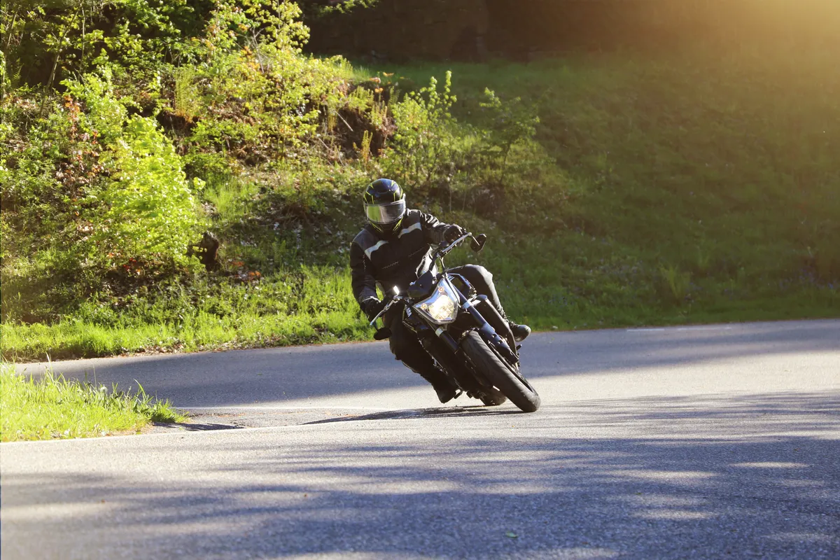  a man riding a motorcycle down a road on a sunny day