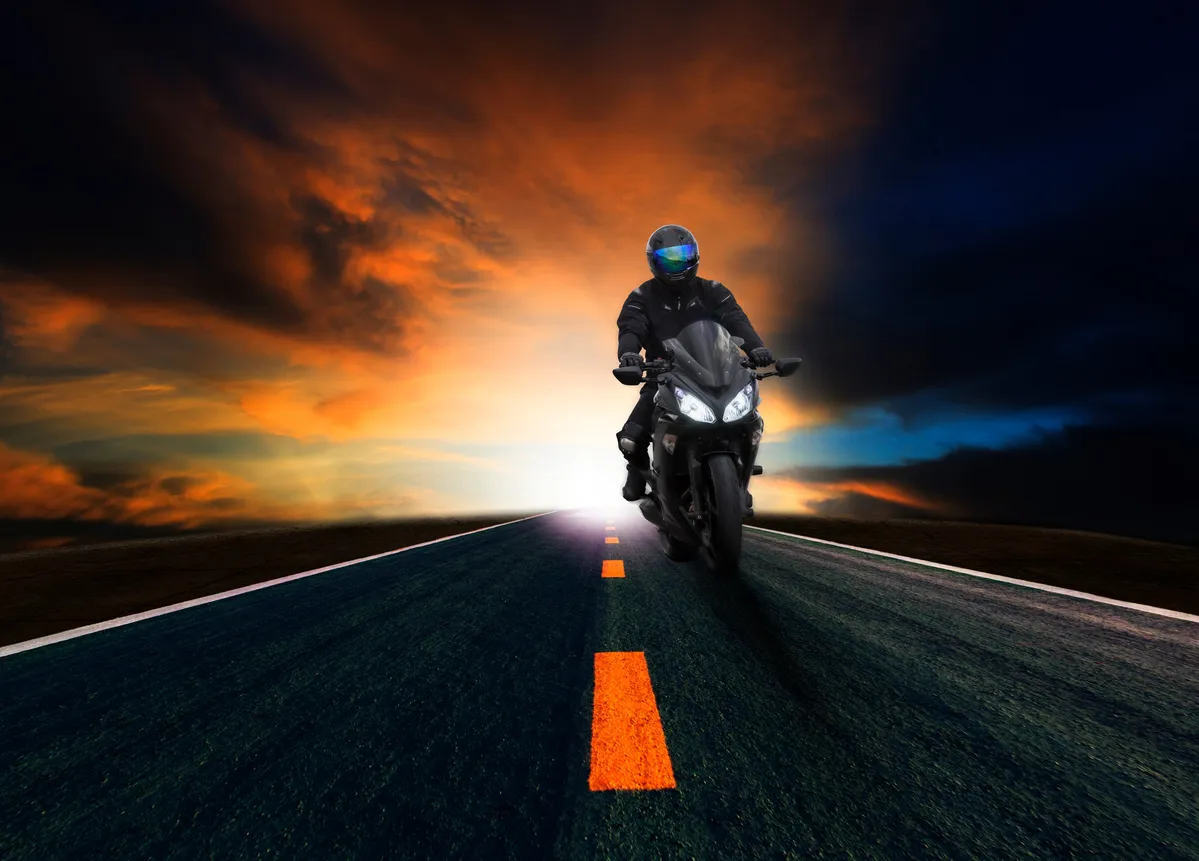  a man riding a motorcycle down the middle of a road