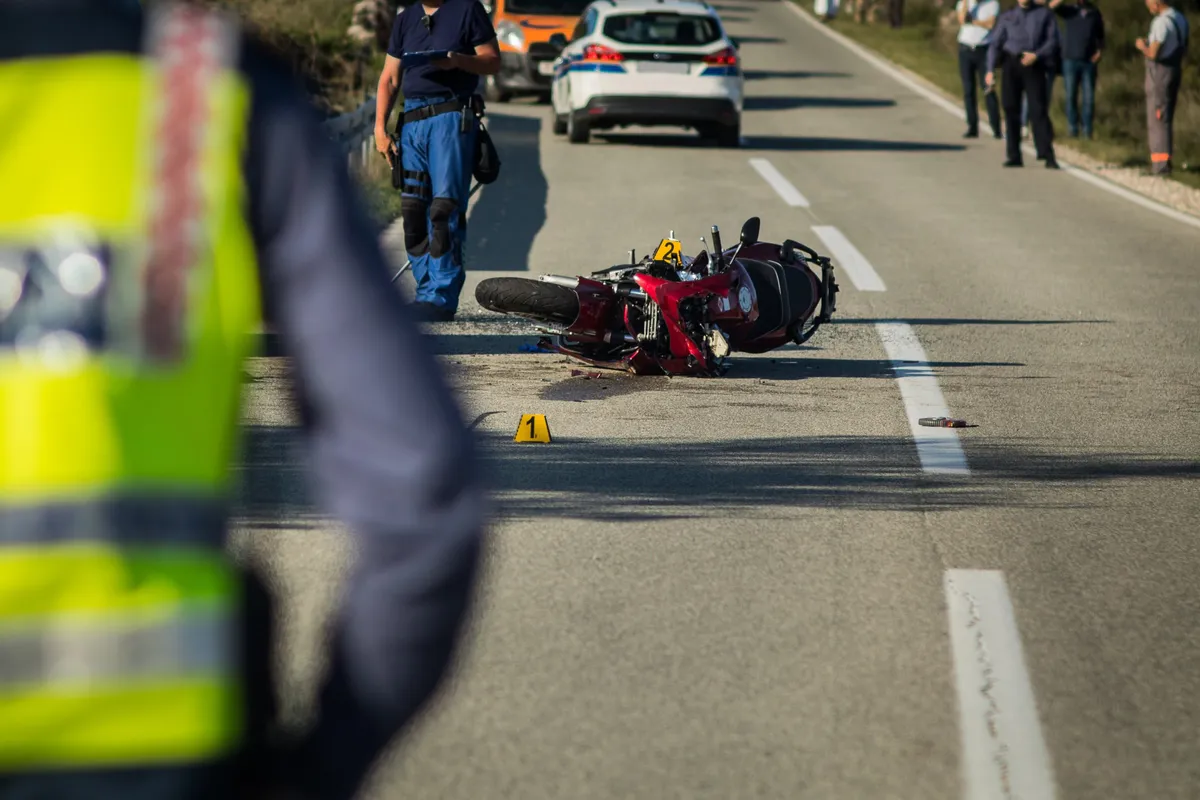 a motorcycle that has been hit by a car on the side of the road