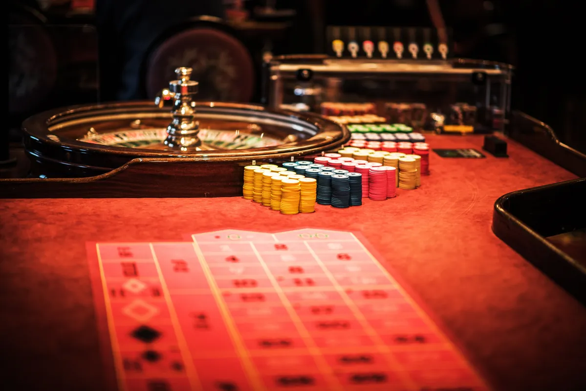  a roulet wheel and a casino table with dice and cards