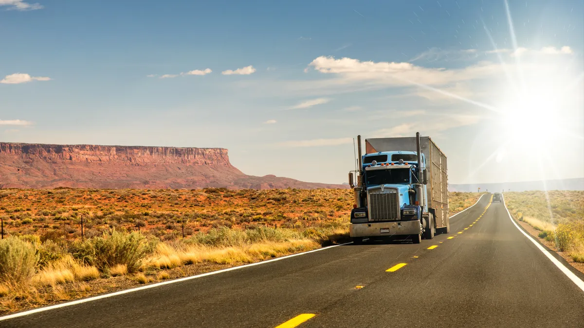 a semi truck driving down the road in the desert