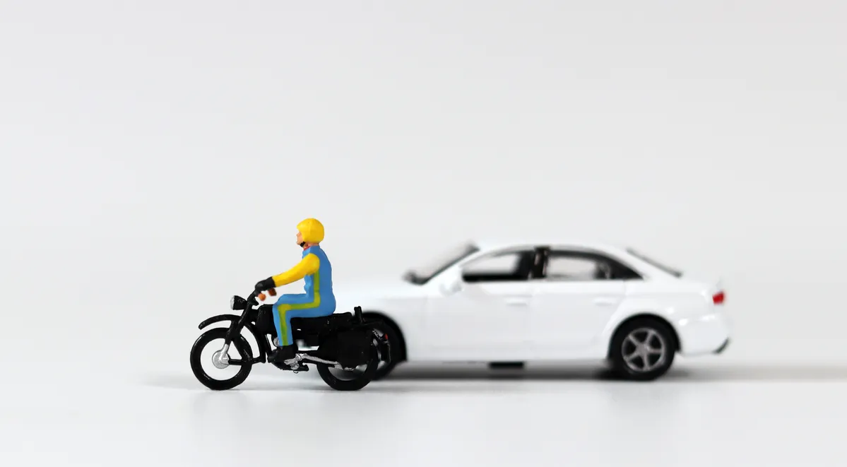  a toy man riding a motorcycle next to a car