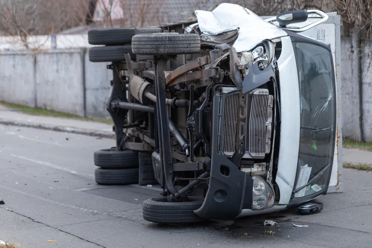  a white truck that has been flipped over on the side of the road