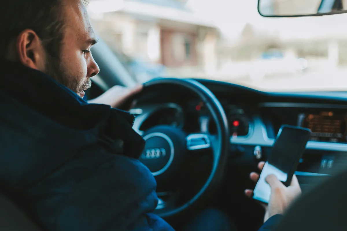 arafed man in a car using a cell phone