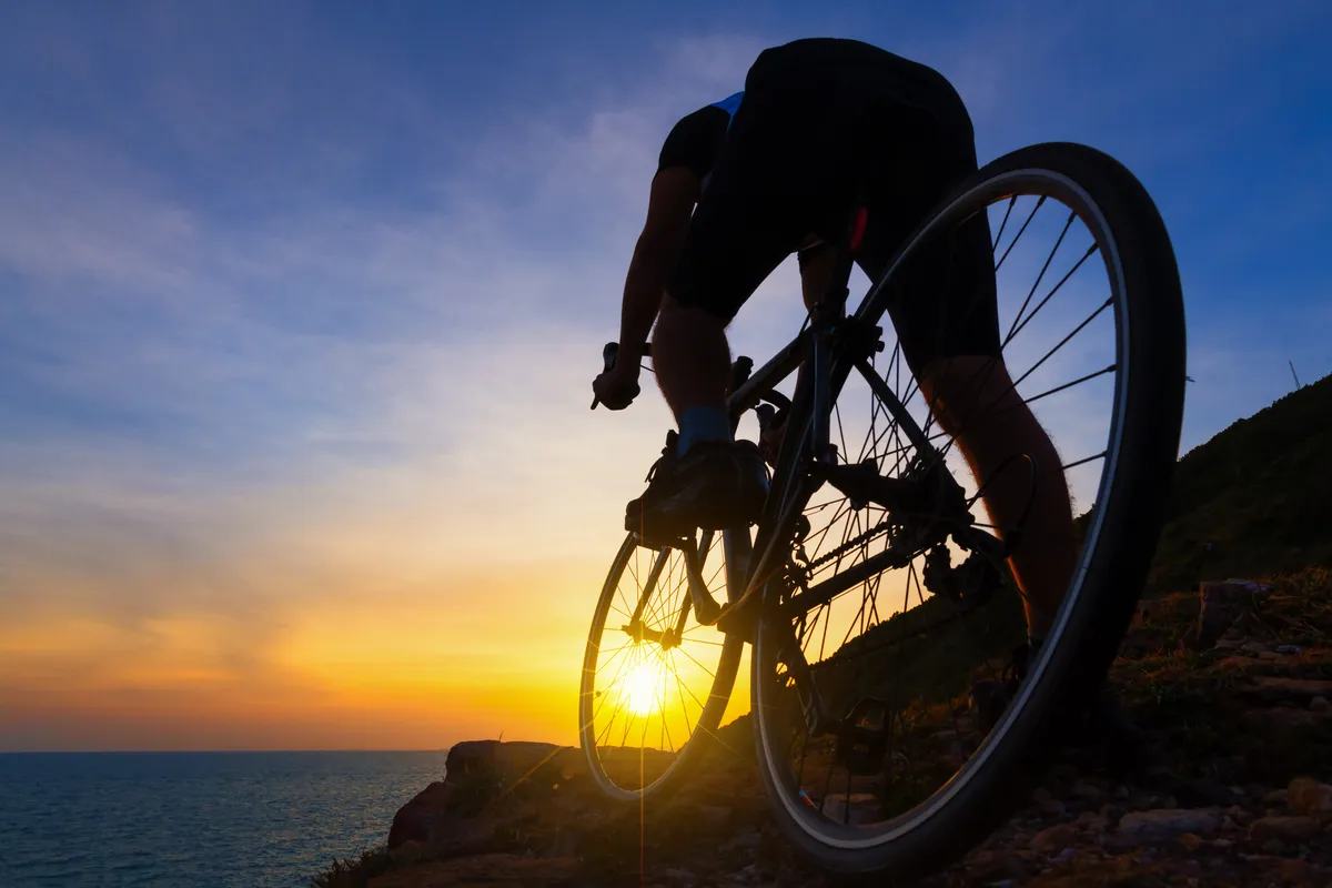 arafed man riding a bike on a rocky hill near the ocean