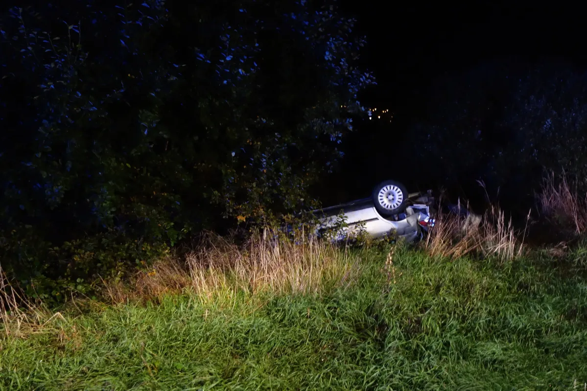 arafed vehicle on its side in a grassy field at night