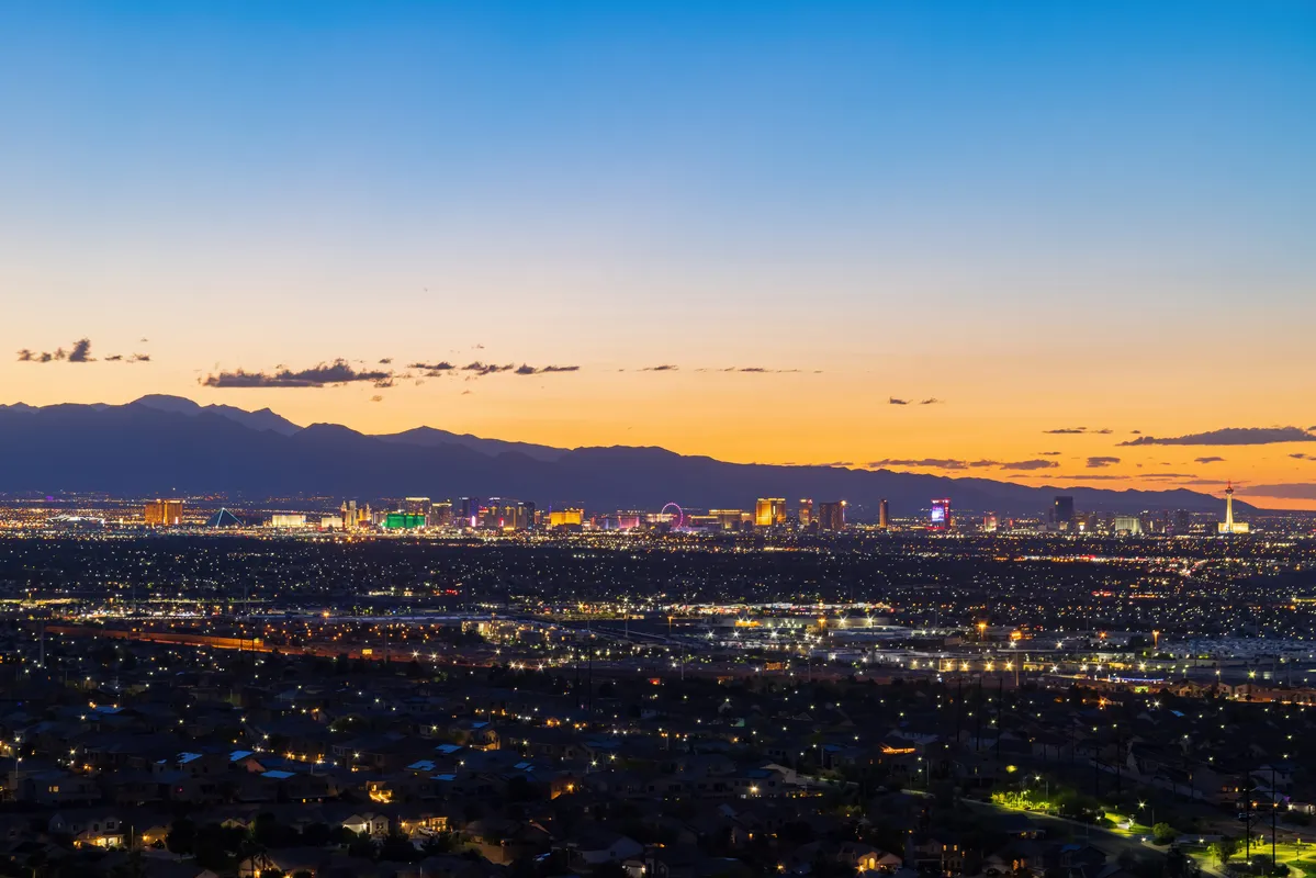 arafed view of a city at dusk with a mountain in the distance