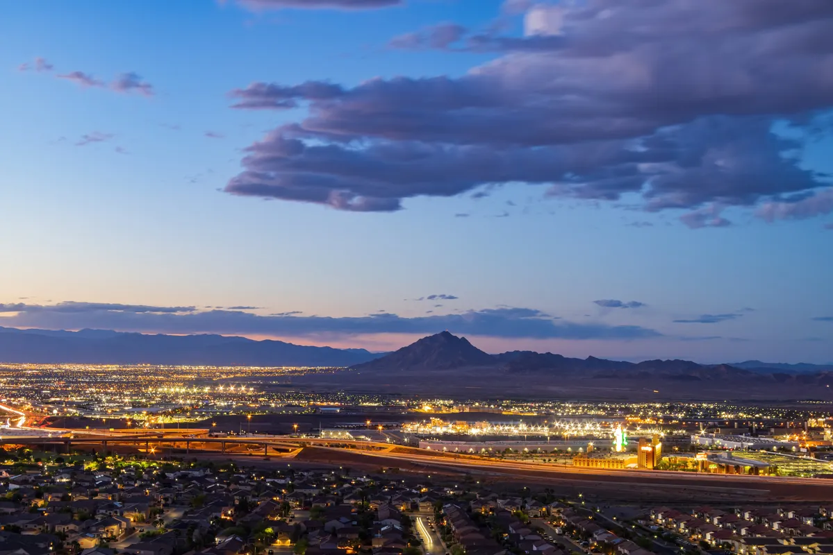 arafed view of a city at night with a mountain in the background