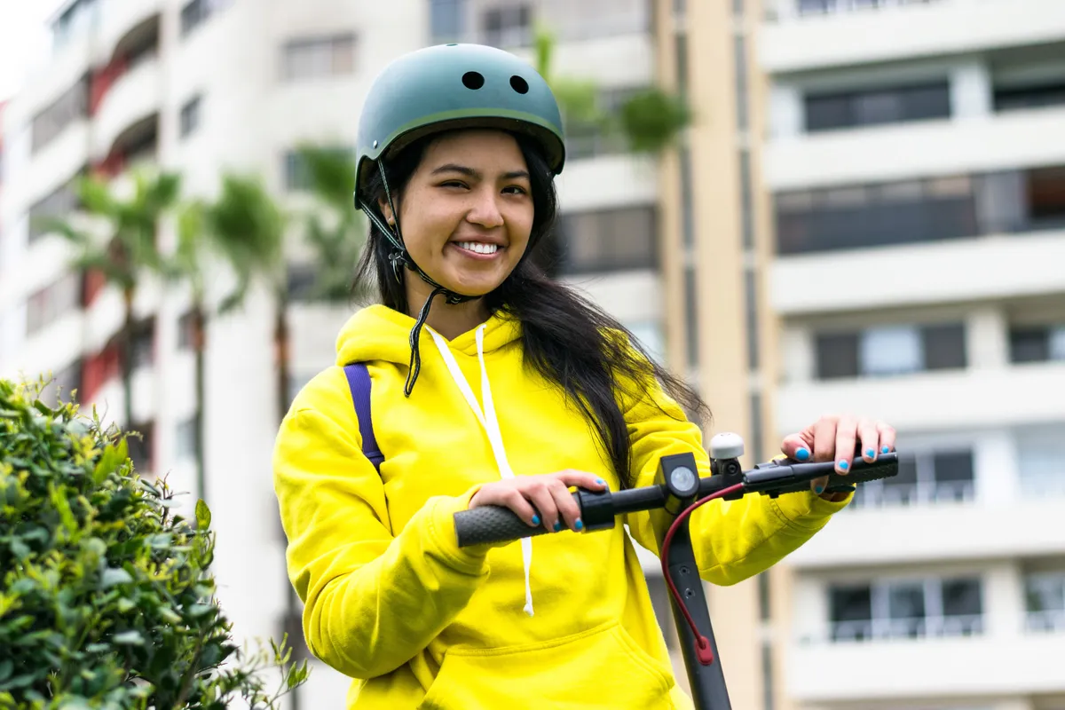 arafed woman in yellow jacket riding a scooter in front of a building