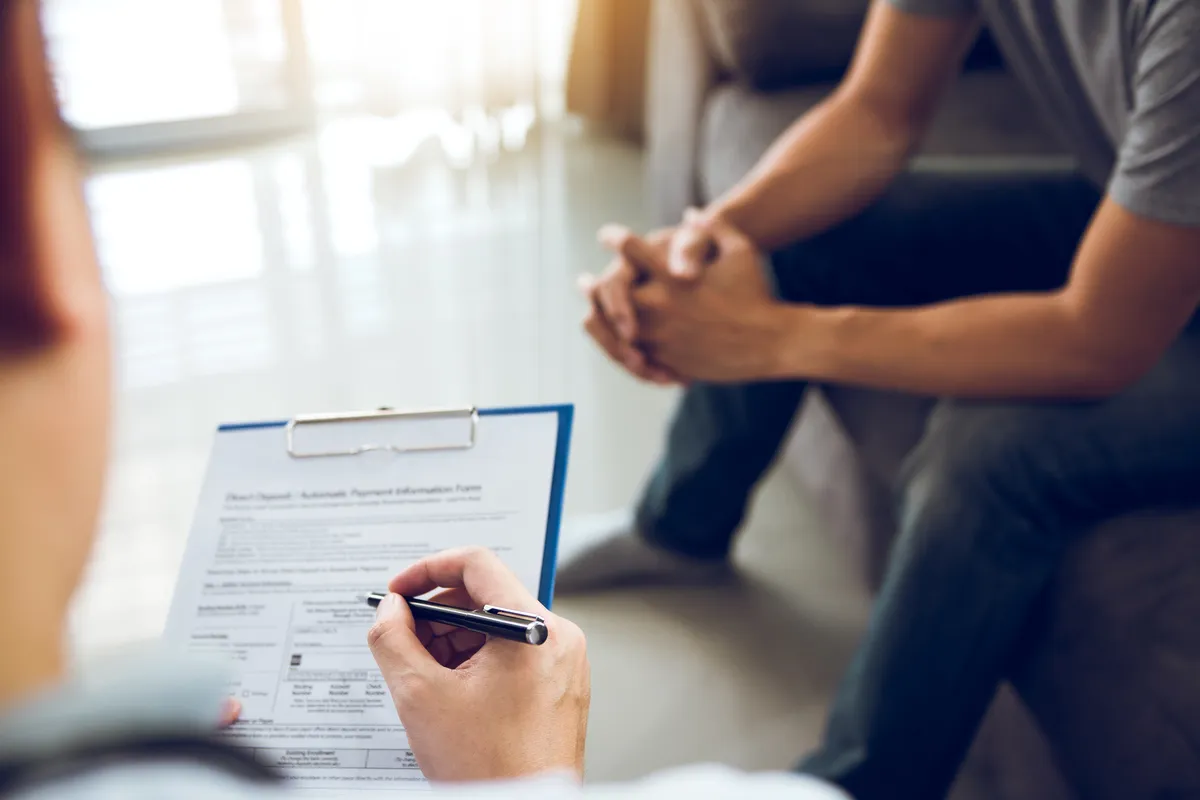 someone is filling out a form of paper with a pen