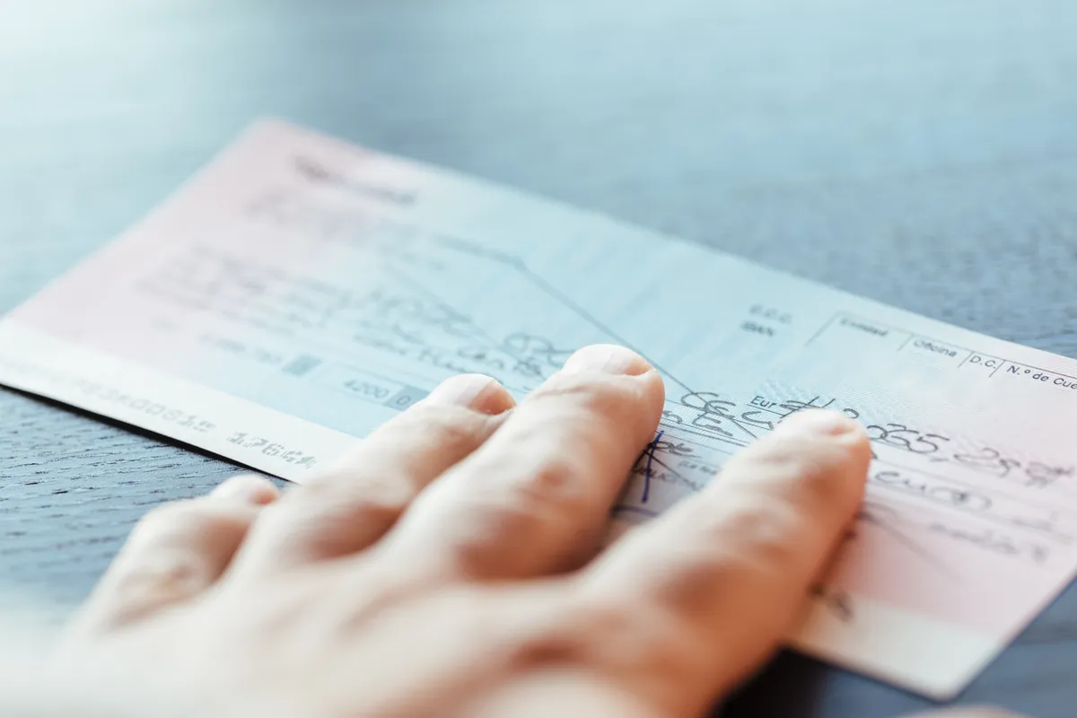 someone is holding a check and pointing at it on a table