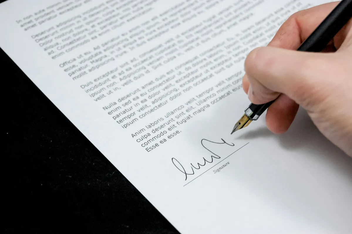 someone is writing a letter with a pen on a piece of paper
