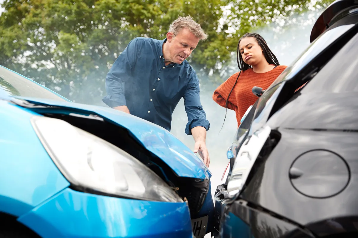  two people looking at a car that has been damaged