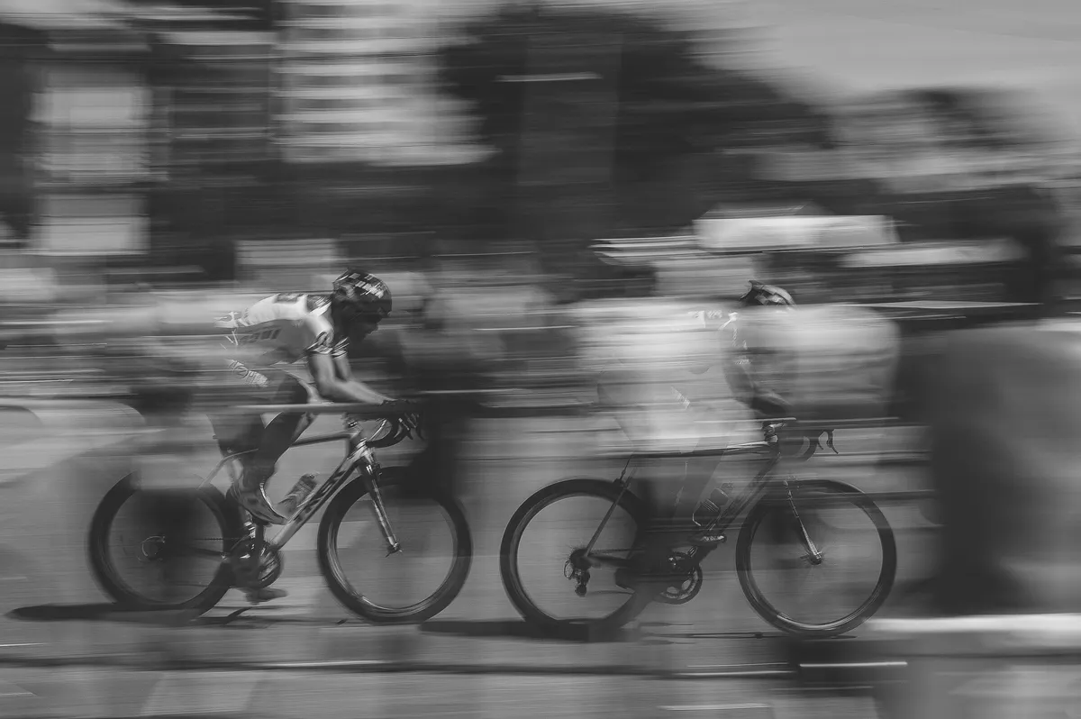  two people riding bikes on a street with blurry background