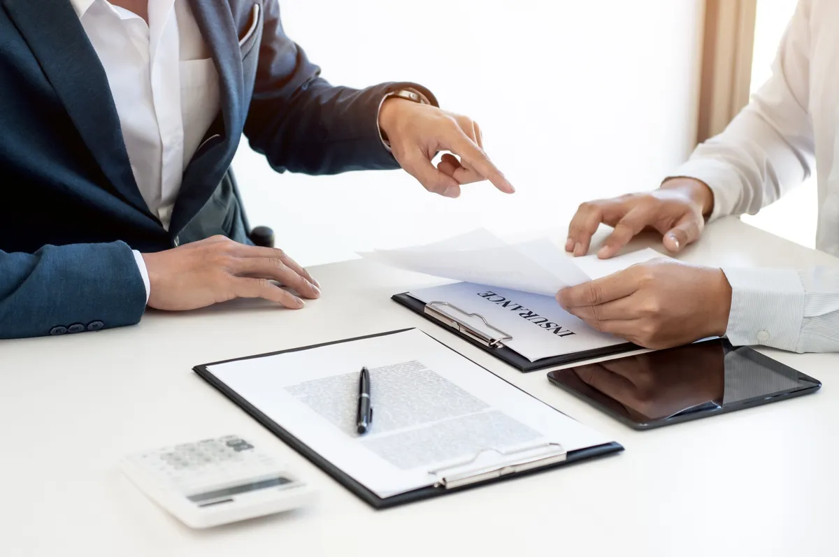two people sitting at a table with papers and a calculator