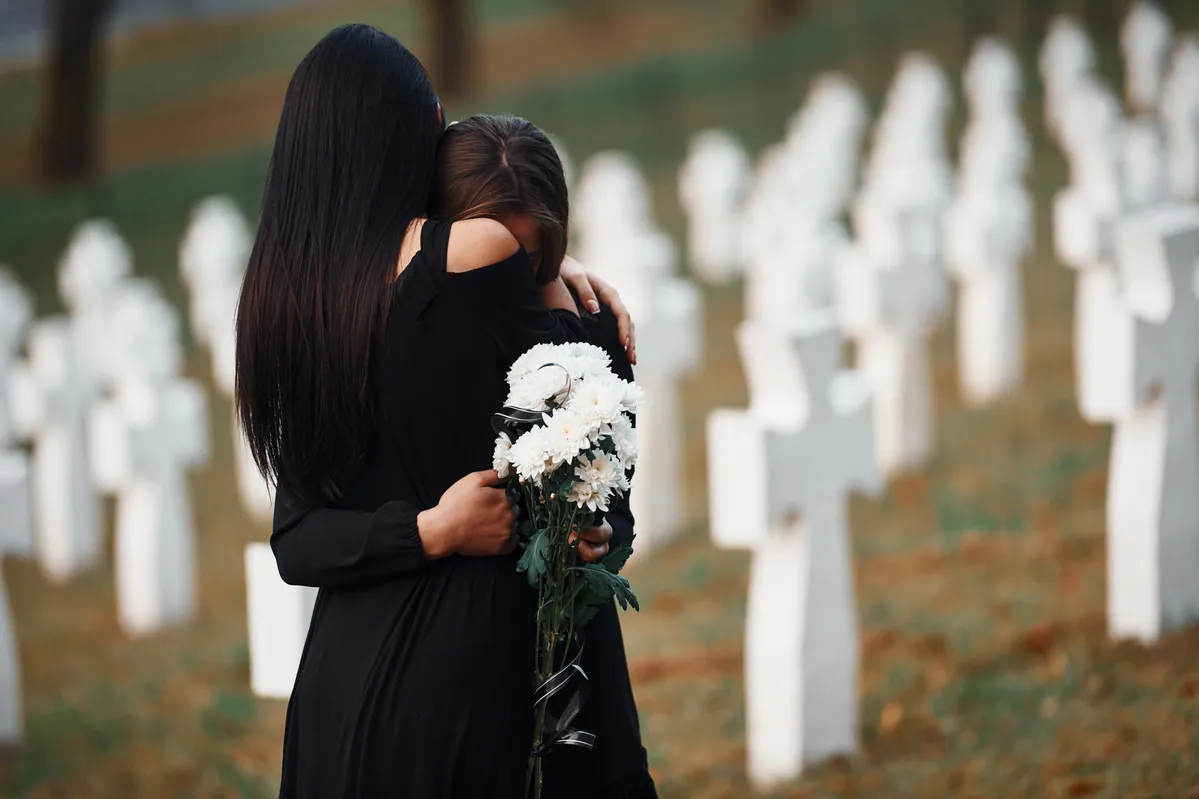  two women hugging each other in a cemetery