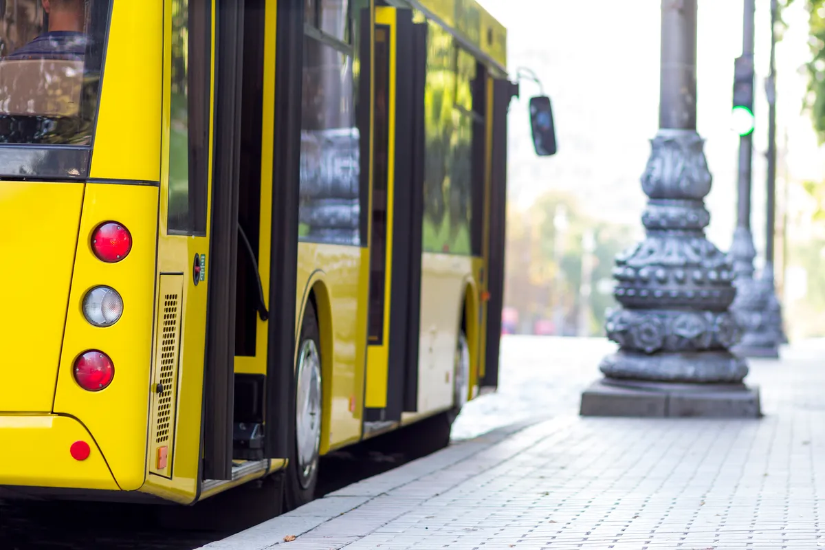 yellow bus parked on the side of the road next to a lamp post